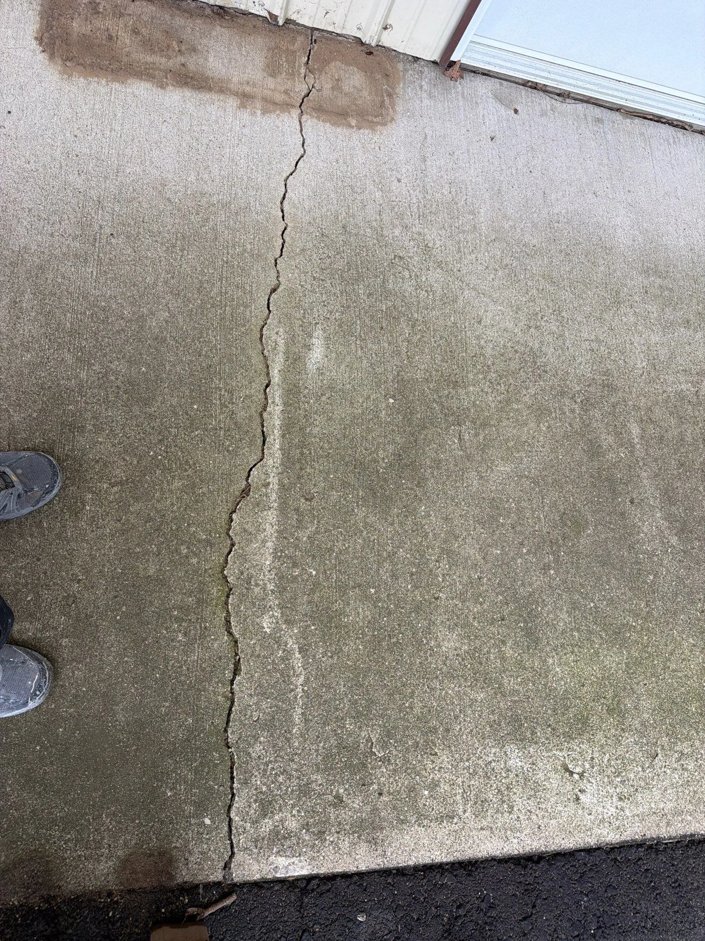 Vertical crack in concrete slab with efflorescence and staining, before repair treatment