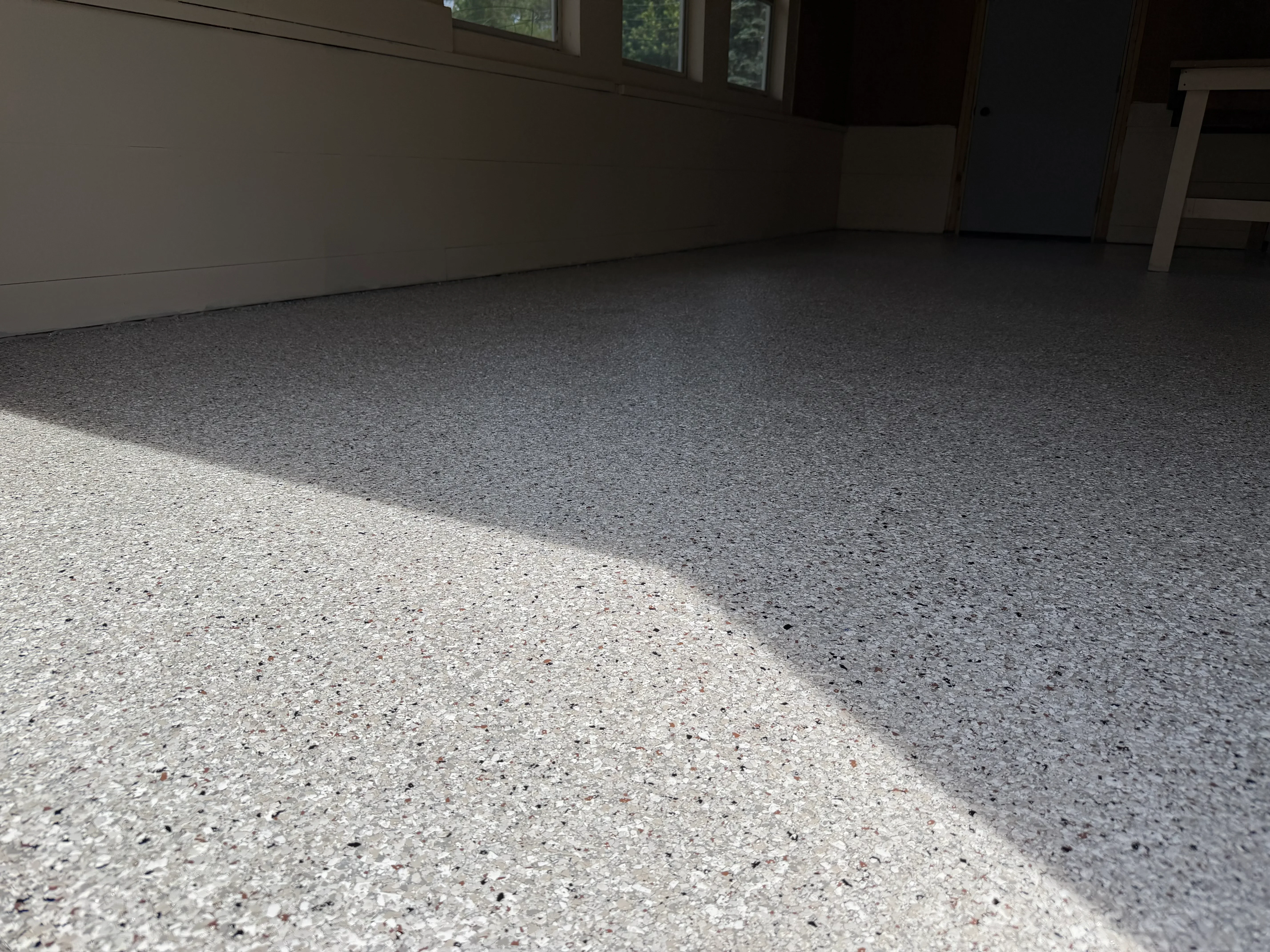 Finished epoxy-coated garage floor with light gray speckled finish and sharp color transition line