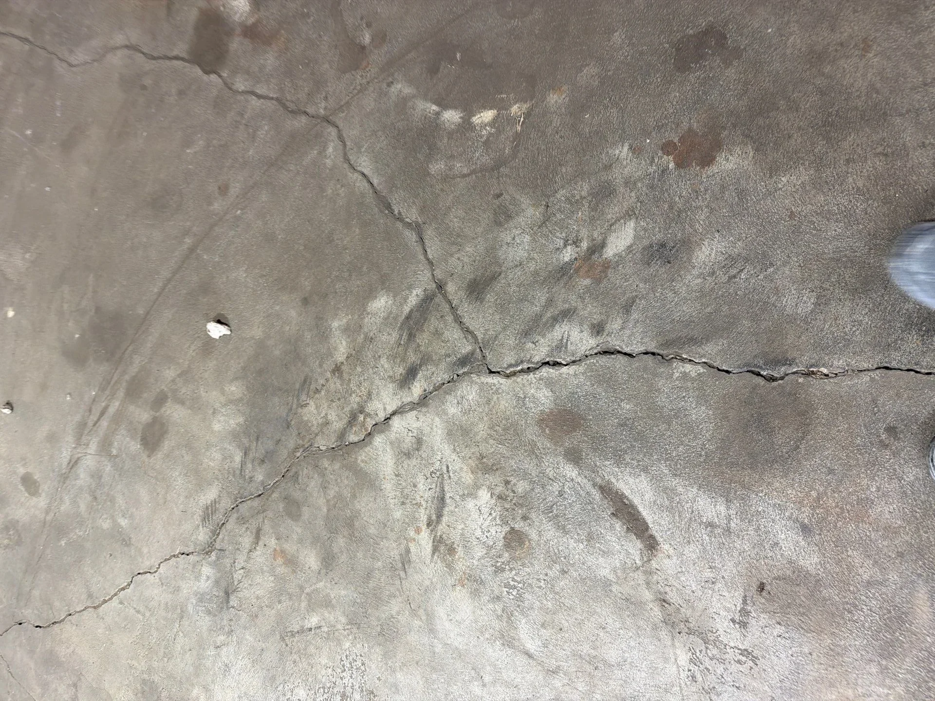 Cracked and weathered concrete surface with visible damage lines and discoloration