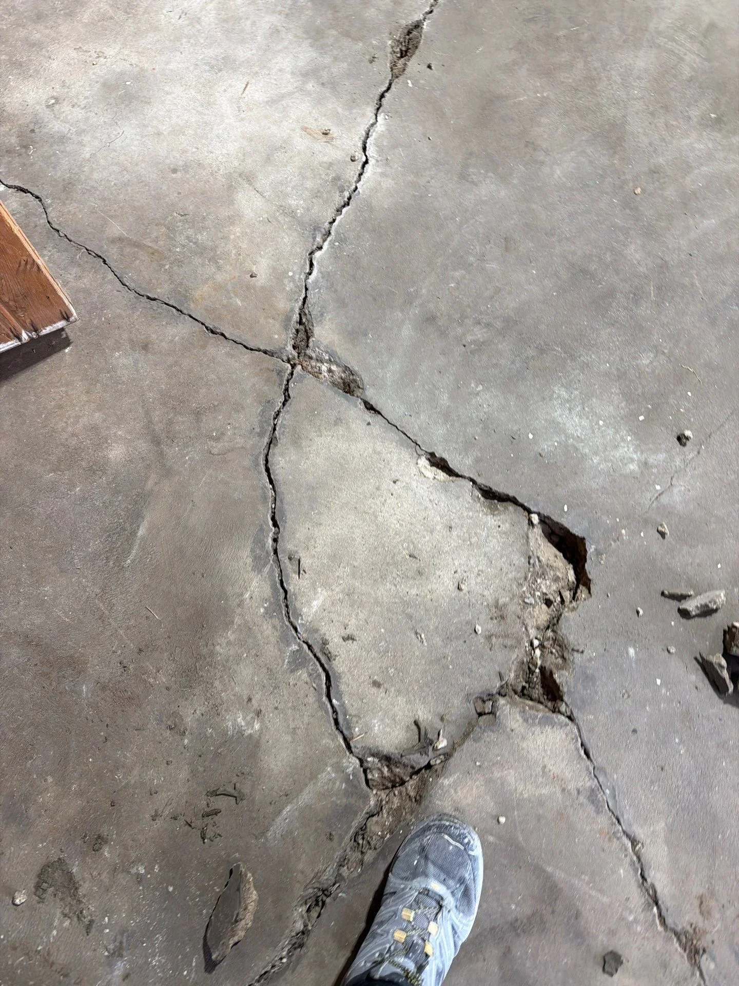 Cracked and spalled concrete surface with deep fissures and displaced sections
