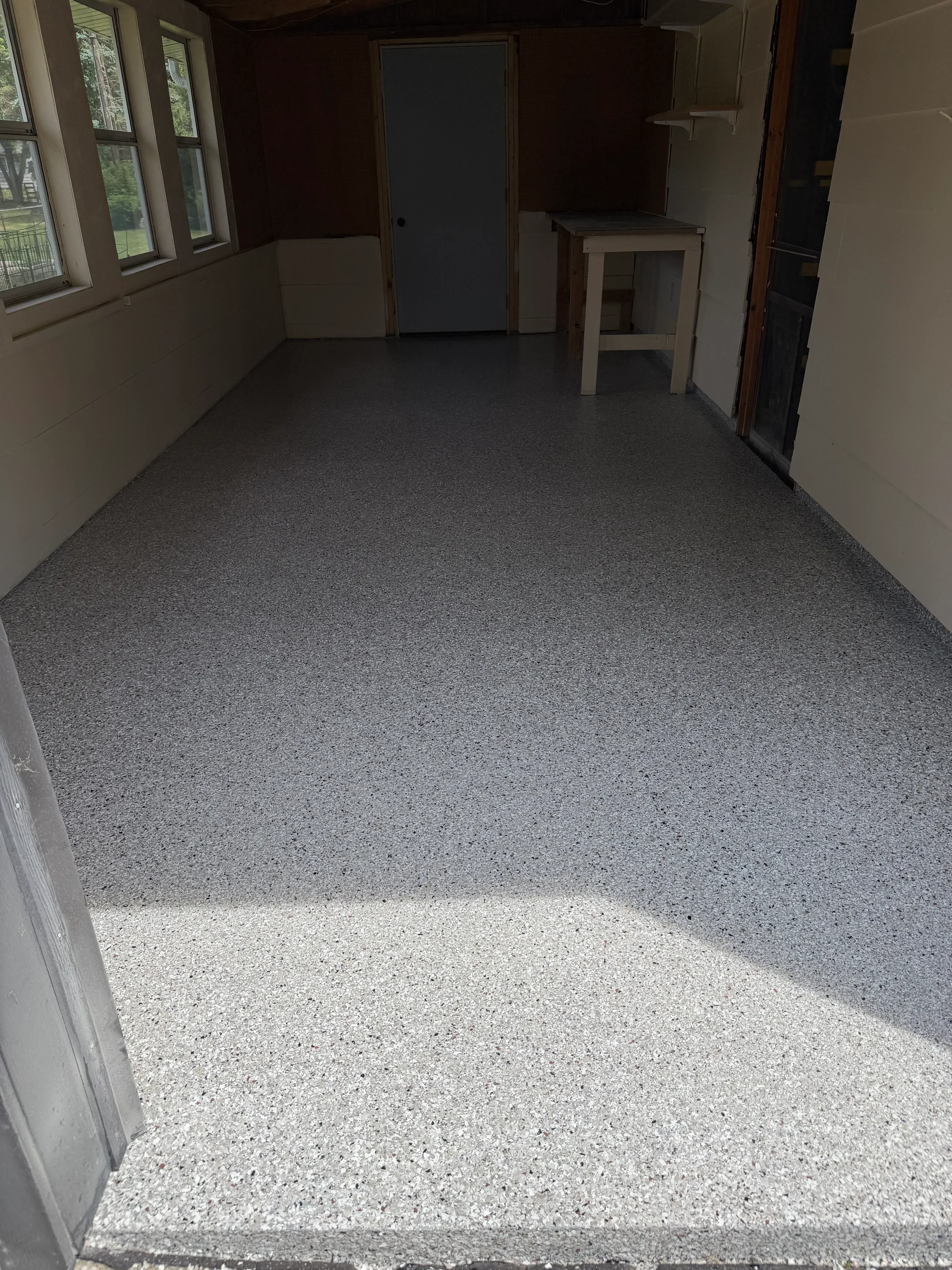 Polished concrete floor with gray epoxy coating in interior room with drywall