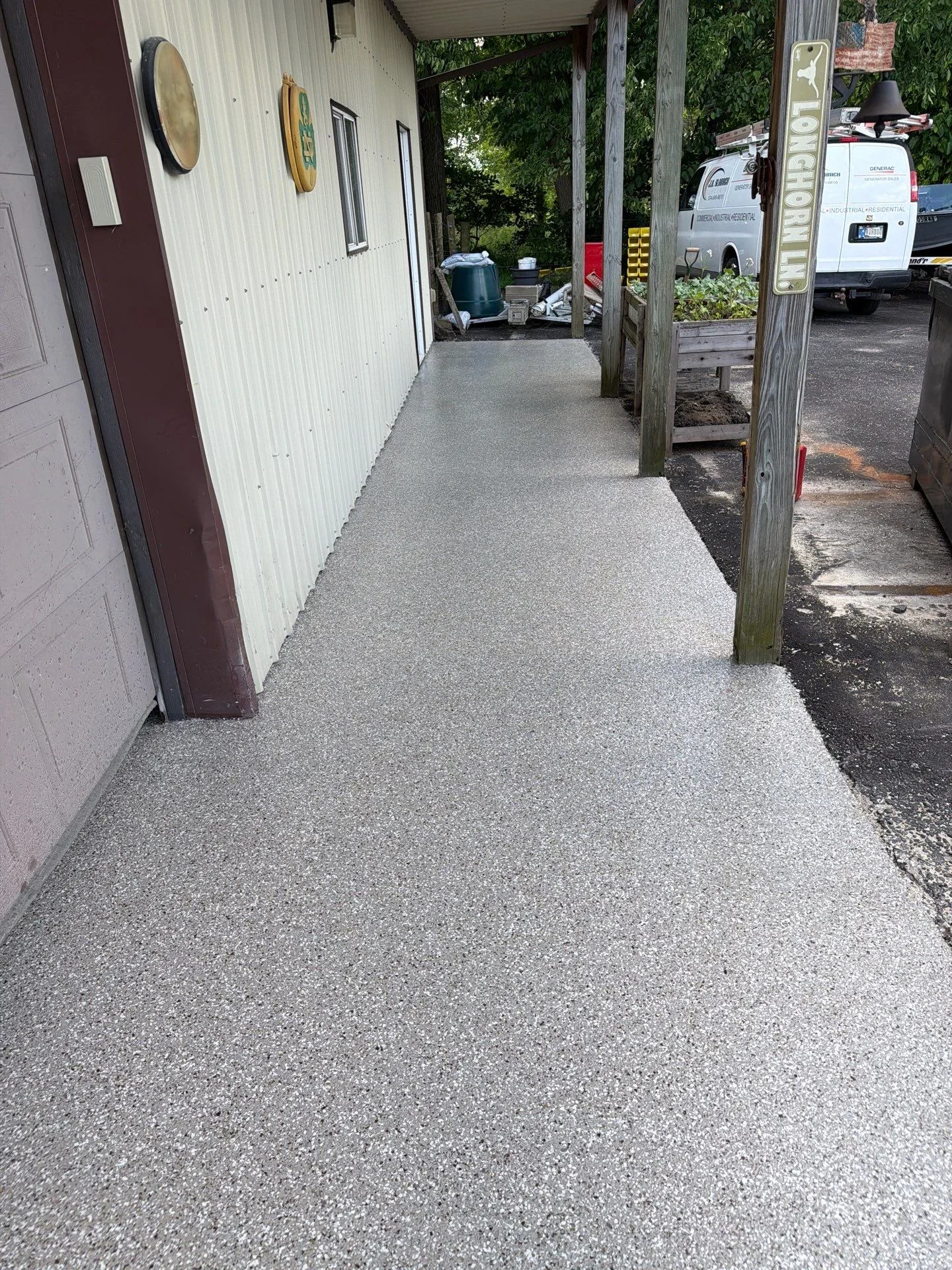 Gray epoxy-coated concrete walkway with smooth aggregate finish along residential structure