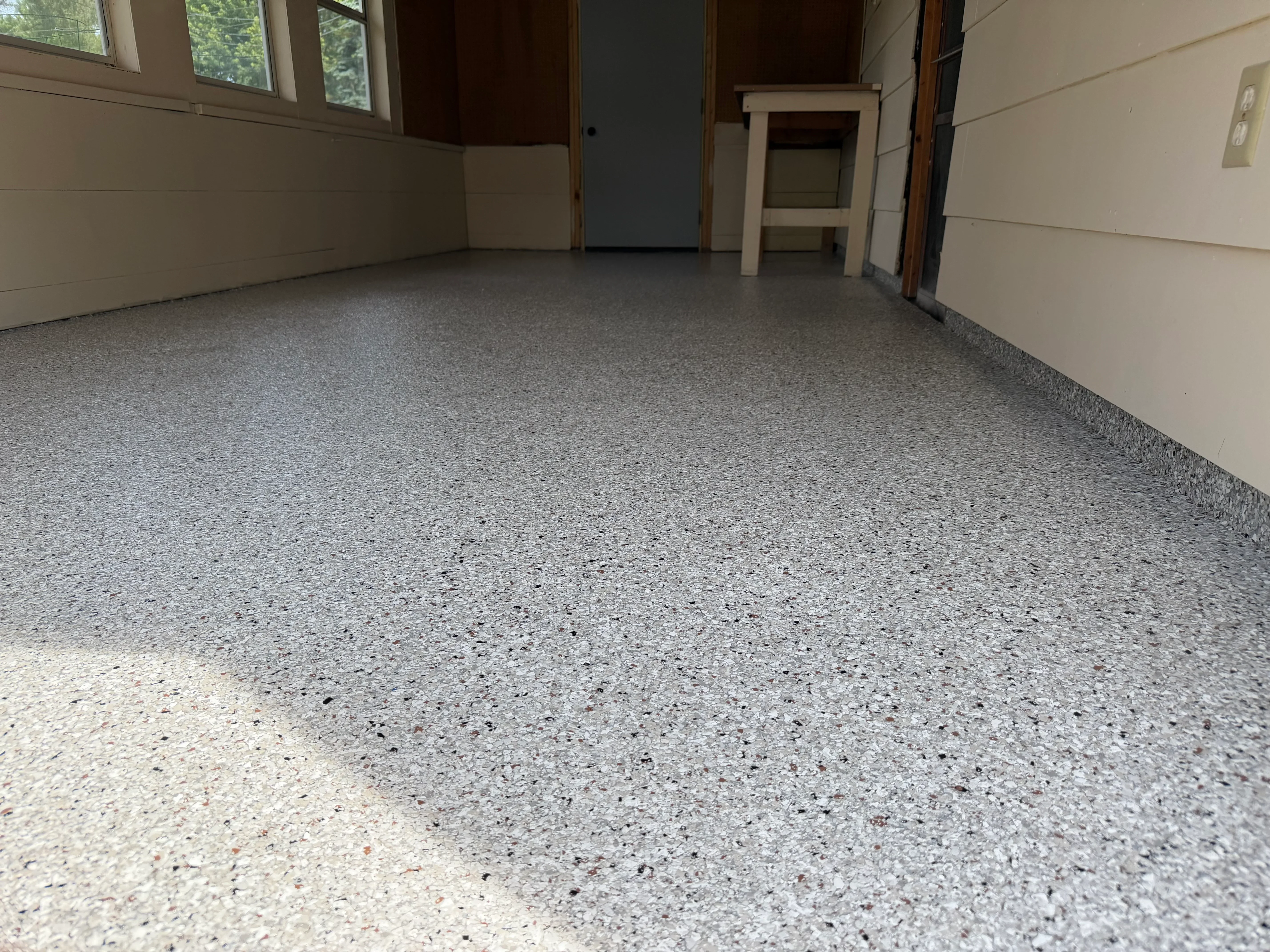 Gray speckled epoxy-coated garage floor with clean, uniform finish and sealed edges