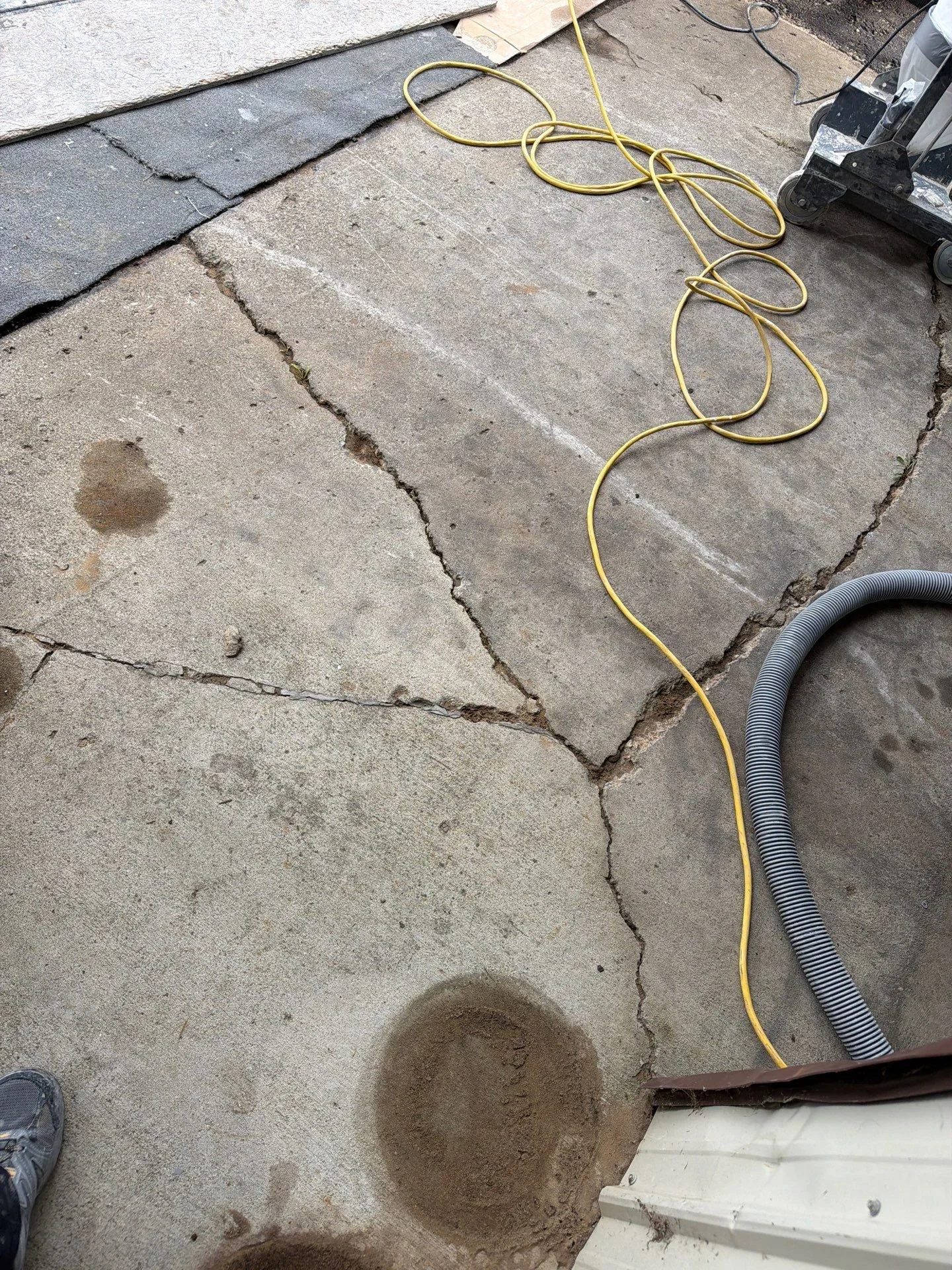 Cracked and spalled concrete slab with water damage, prepared for repair and coating work