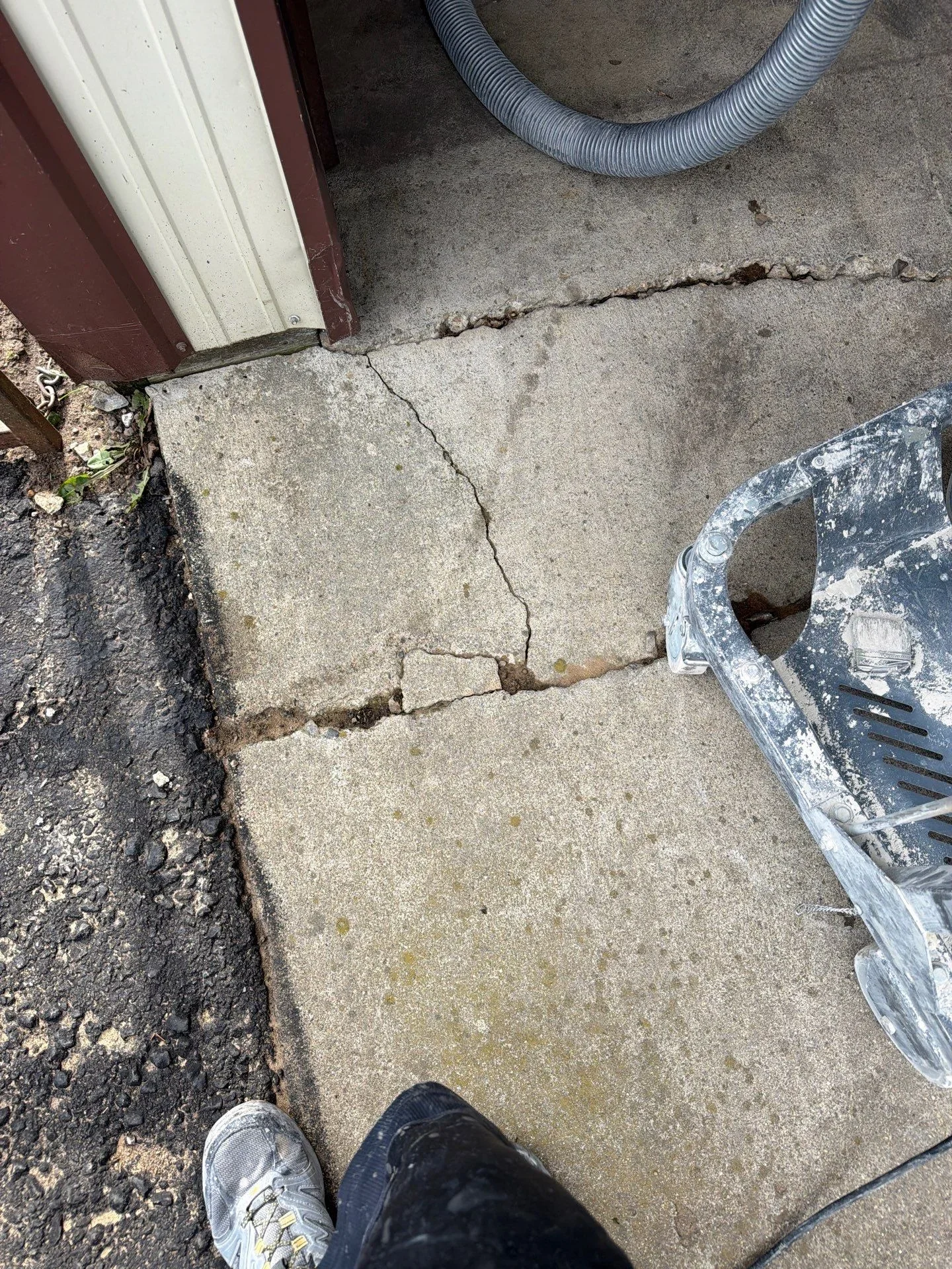 Concrete foundation with repaired crack near building entry and downspout