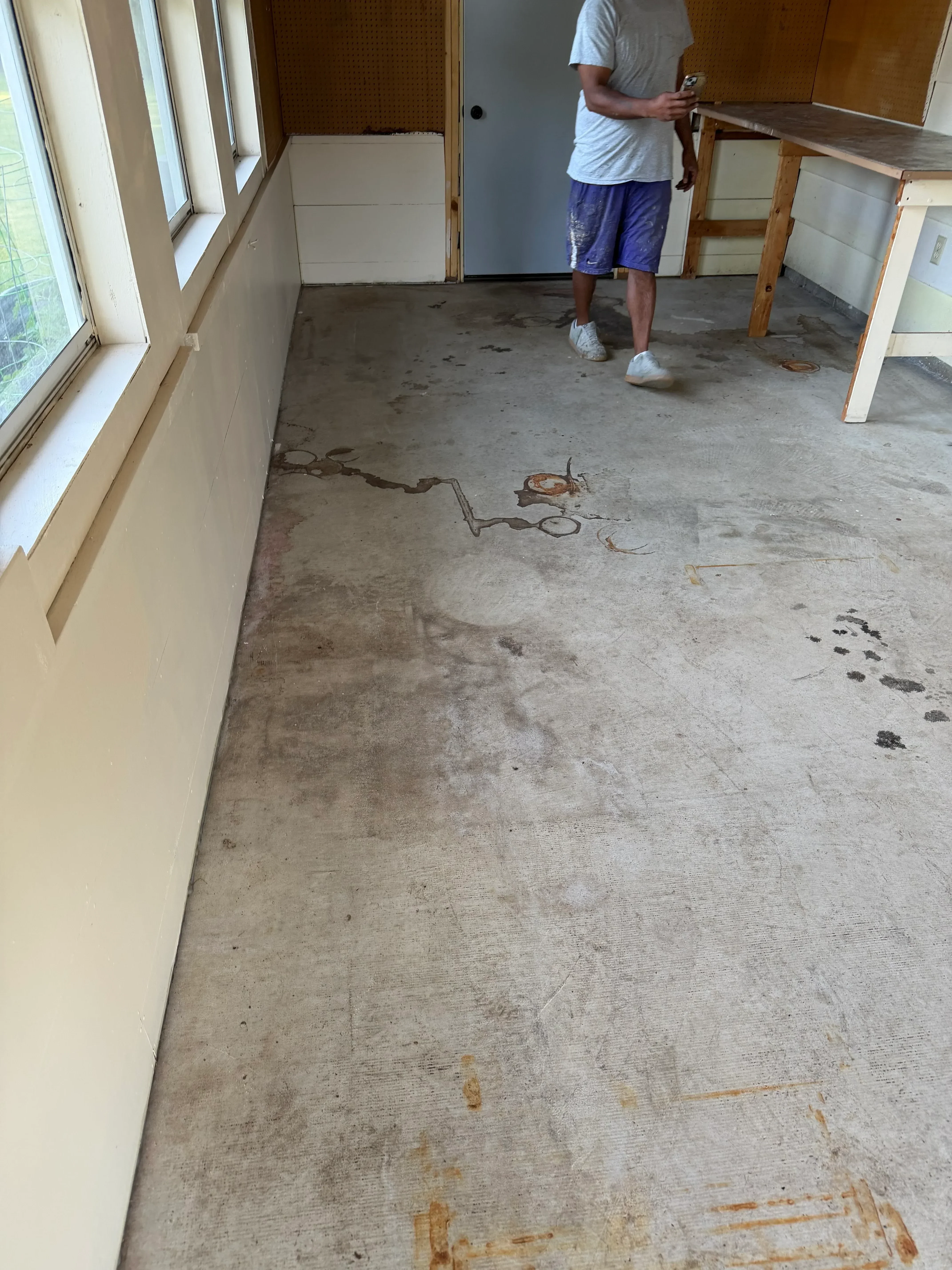 Concrete floor preparation with stripped substrate and coating application in progress