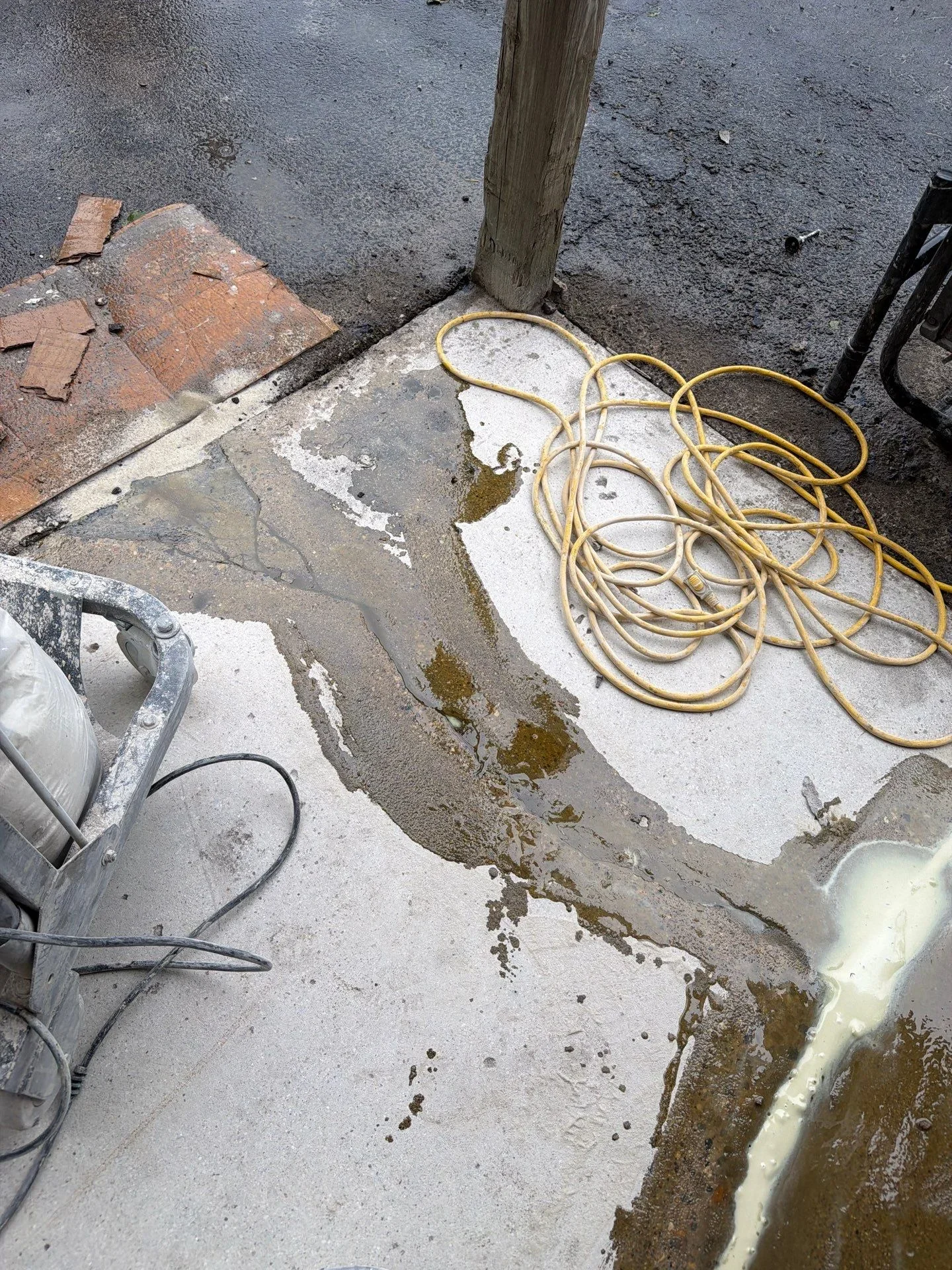 Concrete pad with white primer coat, old coating removal, and prep work in progress