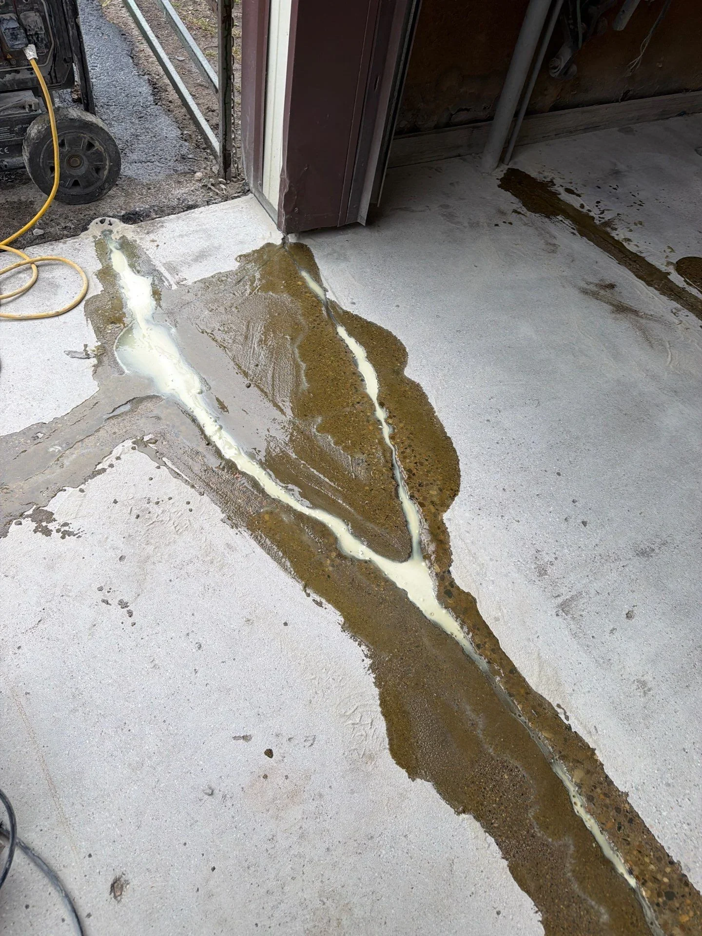 Concrete floor crack filled with white epoxy sealant, garage entrance area